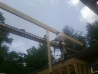 Carpenter setting a ridge beam over a new addition frame — Ice Dam Removal by Roofing Brothers in Goldsmith