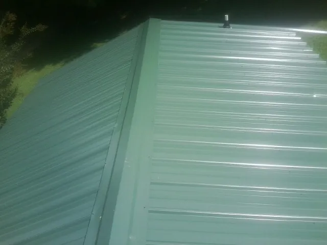 New green metal panels meeting at the ridge of a roof — Flat Roof Repair work by our crew in Goldsmith