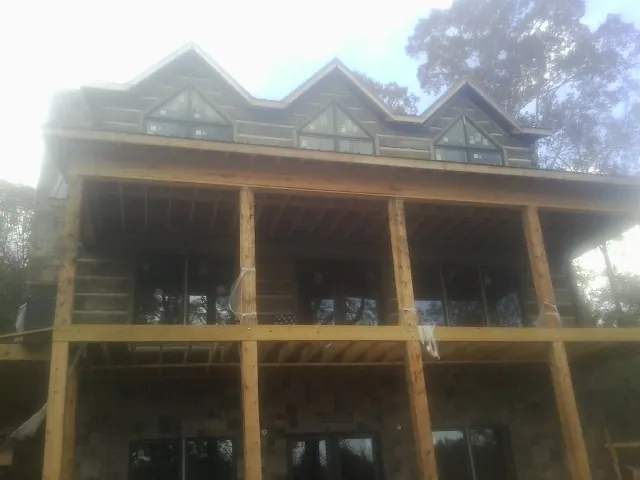 Dormers and porch framing on a large log home under construction — Roof Coating work by our crew in Goldsmith
