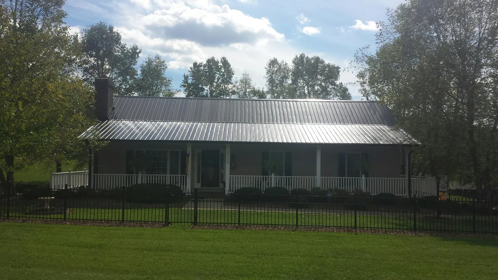 Gray metal roof on a brick ranch with a full width front porch — Gutter Guard Installation work by our crew in Goldsmith