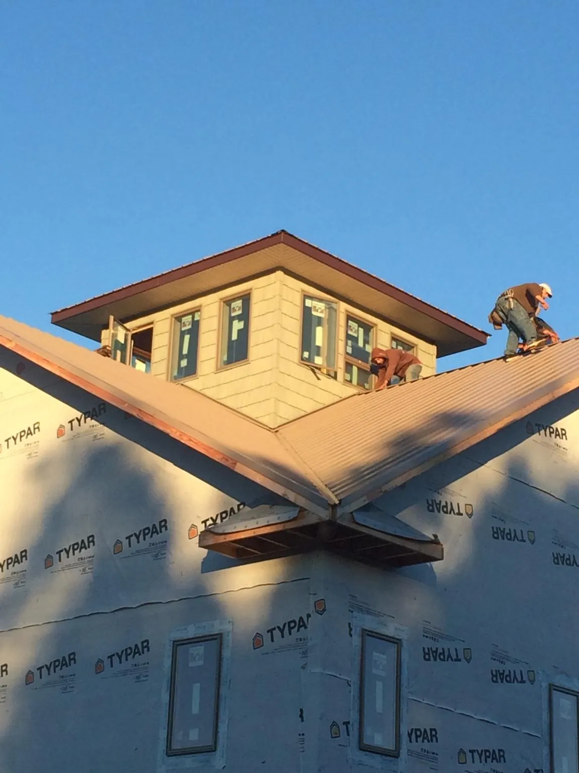 Roofers working around a rooftop cupola on a new metal roof at sunset — Roof Waterproofing in Goldsmith by Roofing Brothers